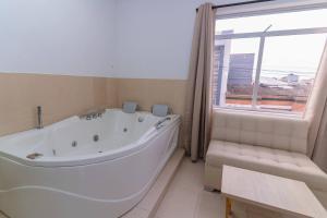 uma casa de banho com uma grande banheira branca e uma janela em Hotel Plataneras Plaza em Apartadó