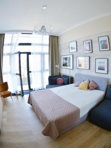een slaapkamer met een groot bed en een blauwe bank bij Apartament 102 - Mielno Dune A - Pool & Beach in Mielno