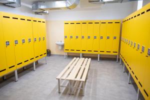 szatnia z żółtymi szafkami i drewnianą ławką w obiekcie Ubytovna a Cykloubytovna Koupaliště Kadaň w mieście Kadaň
