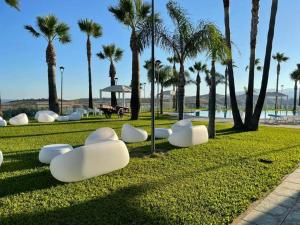 Partenone Resort Hotel في رياس مارينا: حديقة بها كراسي بيضاء وأشجار نخيل