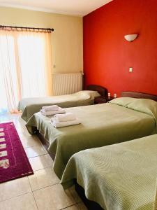 um quarto com três camas e uma parede vermelha em Asteras Hotel em Naousa Imathias