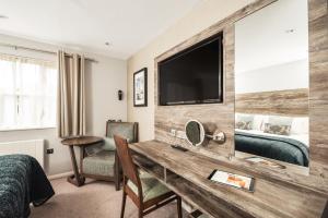 a hotel room with a desk and a tv at Drift Inn at Wyboston Lakes in Saint Neots +28 photos