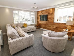 a living room with two couches and a tv at Bryn Derw in Moelfre