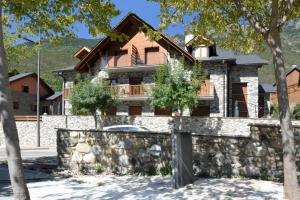 ein Haus mit einem Steinzaun und einer Steinmauer in der Unterkunft Chardín de Llis-Apartamentos Chardins in Benasque