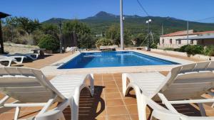 una piscina con 2 sillas de jardín y un par en Casa Levante - Casa Rural Los Cuatro Vientos, en Moratalla