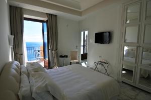 Schlafzimmer mit einem großen weißen Bett und einem Balkon in der Unterkunft Hotel Metropole Taormina in Taormina