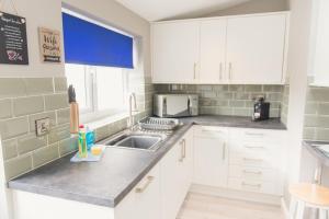 a kitchen with white cabinets and a sink at Charming 6 Bedroom House ALL with en-suite - Large Garden in Tamworth