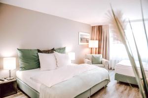 a bedroom with a large white bed and a chair at Concorde Business Boutique Hotel in Bad Soden am Taunus