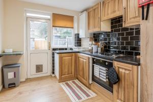 a kitchen with wooden cabinets and a stove top oven at Beautiful 2-Bed House in quiet cul-de-sac in Barking