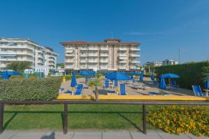 una spiaggia con sedie blu e ombrelloni e un edificio di Residence Zeta Immobiliare Pacella a Lido di Jesolo