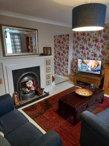 a living room with a fireplace and a tv at The Hideaway in Peebles