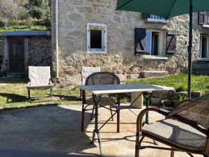 Ein Tisch, zwei Stühle und ein Sonnenschirm vor einem Gebäude in der Unterkunft Bas De Maison in Olivese