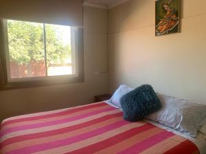 een slaapkamer met een bed met een deken en een raam bij Casa conferencia in Santiago