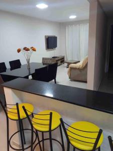 a living room with a table and yellow chairs at Apto excelente à 50m do parque de águas termais in Piratuba