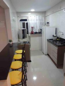 a kitchen with a counter and some chairs in it at Apto excelente à 50m do parque de águas termais in Piratuba