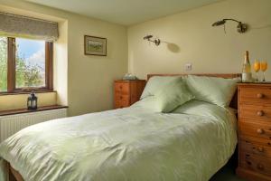 a bedroom with a white bed with a dresser and a window at Finest Retreats - Dolwar Cottage in Ffestiniog
