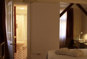 a bedroom with a bed and a bathroom with a toilet at Hotel Boutique Casa Conde in Santiago