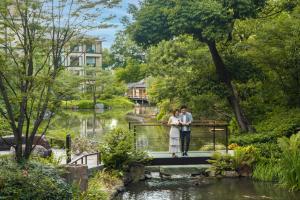 Una novia y un novio parados en un puente sobre un estanque en Four Seasons Hotel Kyoto en Kyoto