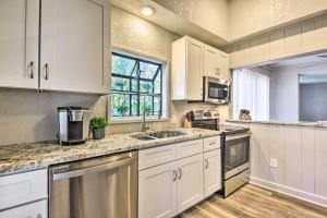 a kitchen with white cabinets and a sink and a window at Port Charlotte Cottage about 3 Mi to Beach Park! in Port Charlotte