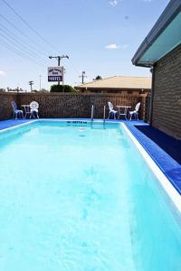 a large blue swimming pool with chairs and a building at Mid Town Inn Narrabri in Narrabri