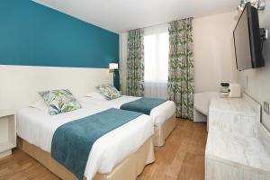 a hotel room with two beds and a television at Logis Hôtel du Centre - Halte idéale en cyclotourisme avec garage à vélos clos in Molsheim +27 photos