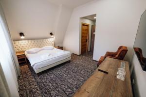 a bedroom with a bed and a wooden table at Popasul Domnesc- Resort& Spa- Voronet Vue in Voronet