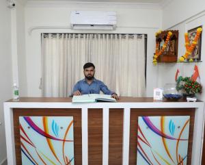 Ein Mann am Schreibtisch mit einem Buch in der Unterkunft Hotel Satyam Residency in Navi Mumbai