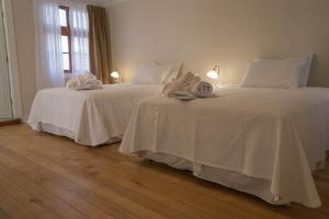 two beds in a bedroom with white sheets at Hotel Boutique Casa Conde in Santiago