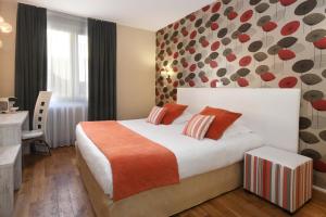 a hotel room with a large bed with orange pillows at Logis Hôtel du Centre - Halte idéale en cyclotourisme avec garage à vélos clos in Molsheim