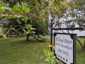 een bord in een park met een huis op de achtergrond bij Hill Road Manor Bed & Breakfast in Grand Falls -Windsor