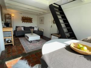 a living room with a couch and a spiral staircase at Slapen op het platteland in Bodegraven