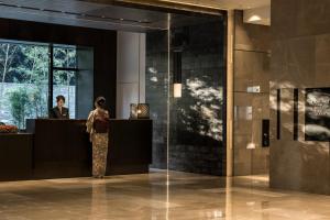 a woman standing at a counter in a lobby at Four Seasons Hotel Kyoto in Kyoto