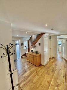 a living room with wooden floors and a staircase at Four Corners Holiday Home Hot Tub & Sauna in Ferndown