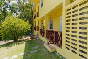 una casa gialla con balcone e cortile di Sephina Villa St Lucia Island Dream Holidays a Cap Estate