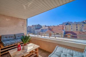 a balcony with a couch and a table and a large window at Le Reverso, T6 en duplex & vue incroyable in Grenoble