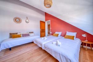 two beds in a room with a red wall at Le Reverso, T6 en duplex & vue incroyable in Grenoble