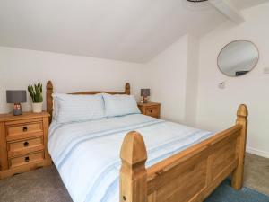 a bedroom with a wooden bed and a mirror at Ickle Pickle Cottage in Thirsk