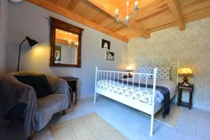 1 dormitorio con cama, silla y espejo en Chez Pique-Fesse Chambre d'hote, en Saint-Martin-lʼArs