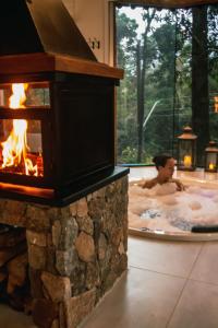 a man in a hot tub with a fireplace at Estalagem Serra de Minas em Monte Verde in Monte Verde