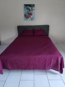 a bed with a purple bedspread on a white floor at confort apto con balcones in Vega Alta