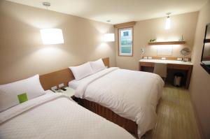 a hotel room with two beds and a sink at Kindness Hotel - Tainan Chihkan Tower in Tainan