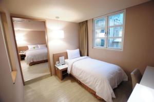 una camera d'albergo con due letti e uno specchio di Kindness Hotel - Tainan Chihkan Tower a Tainan