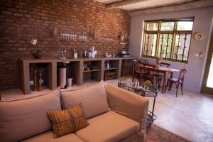 a living room with a couch and a brick wall at The Onion Cottage in Nieu-Bethesda