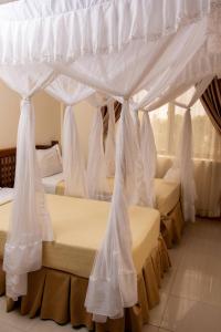 a row of beds in a room with white drapes at Briston Hotel in Arusha