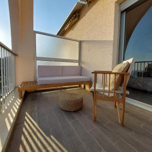 um alpendre com um banco e uma cadeira numa varanda em Un balcon sur la mer em Ajaccio