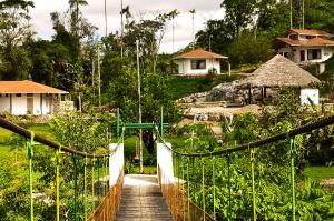 a suspension bridge with a wooden walkway in a village at AMUNTAI RAINFOREST LODGE in Palora