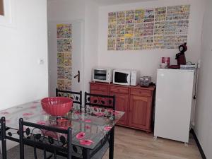 uma cozinha com uma mesa e um frigorífico branco em Appartement le labyrinthe du peintre em Bransat