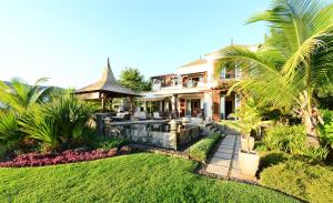 ein Haus mit einem Garten und einer Liegewiese mit Palmen in der Unterkunft Heritage The Villas in Bel Ombre
