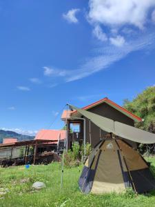 a tent in the grass in front of a building at Sinurambi 2 in Kundasang