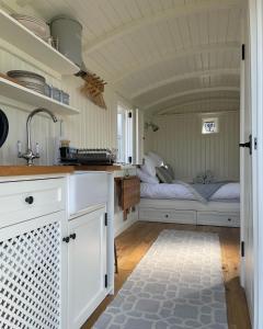 eine Küche mit weißen Schränken und ein Bett in einem Zimmer in der Unterkunft The Hut by the River in York
